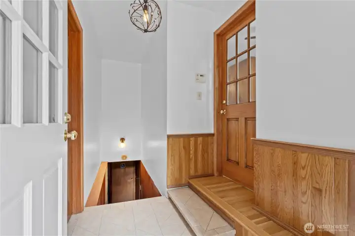 Back door from driveway. Closed door on right leads to kitchen, and stairs lead down to the basement.