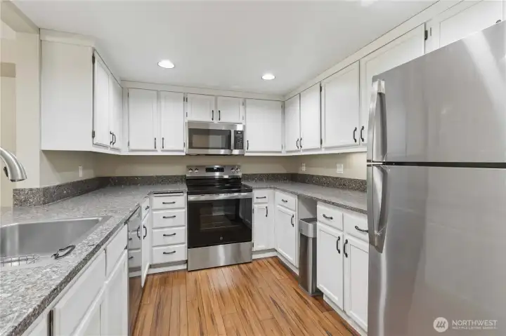 Kitchen with can lights, stone countertops and new appliances.