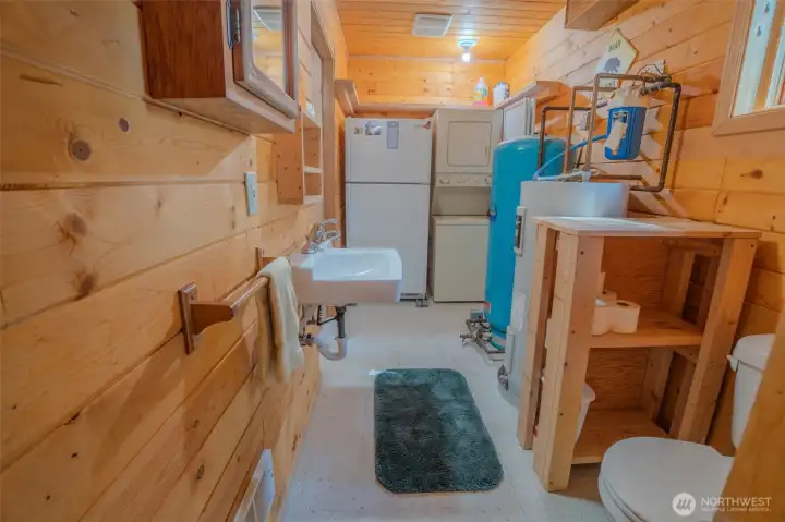 Bathroom/utility room with fridge and laundry.