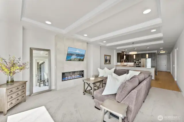 The living area offers ample room for both relaxation and entertaining, while the adjacent kitchen features modern cabinetry, stainless steel appliances, and spacious bar seating.