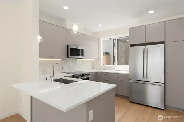 Photos of model home with similar finishes & floor plan. Crisp, white kitchen design with central island and space to gather—where style meets function.
