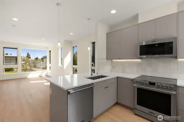 Photos of model home with similar finishes & floor plan. Close-up of kitchen features: tile backsplash, under-cabinet lighting, and polished countertops.