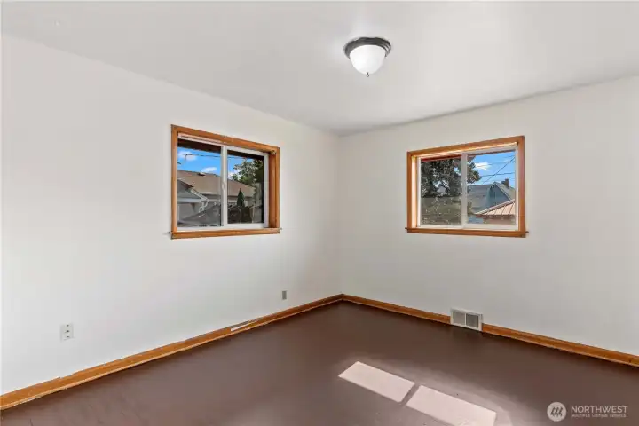 A bright and empty bedroom with beautiful wood trim and large windows, providing a clean slate for its next owner to make it their own.