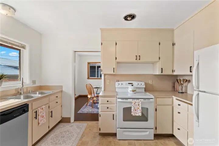 A bright and inviting kitchen that features plenty of cabinet storage, a large window over the sink, and a layout perfect for cooking and entertaining.