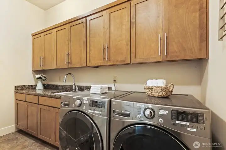Spacious laundry room on the main floor with newer washer and dryer (installed in 2018), storage space, and built-in drying racks.