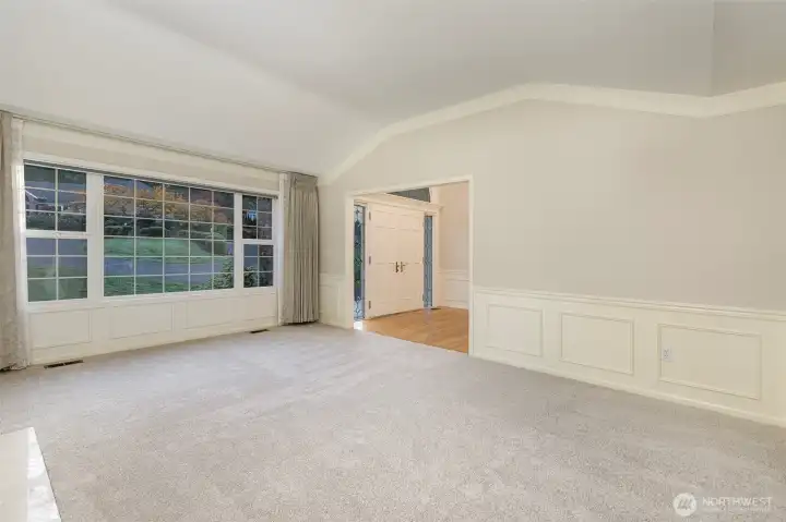 Formal living room is bright and sunny with large windows and raised ceilings.