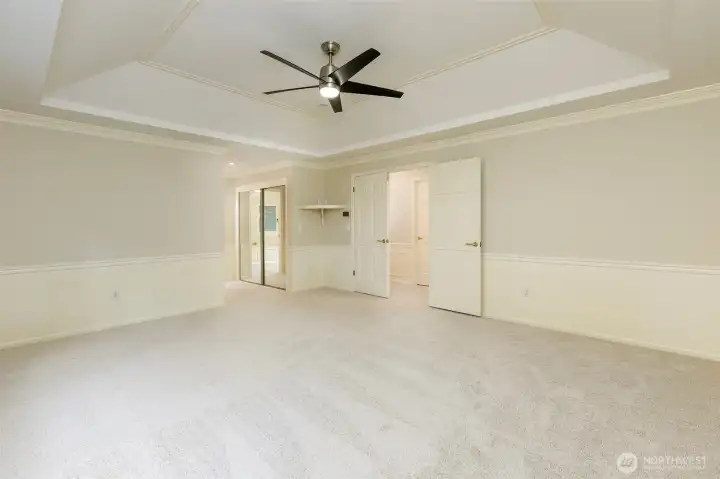 The primary suite features a beautiful ceiling with crown molding.    In the background are two large closets (one a walk-in) with closet organizers and the 5 piece master bath down the hall.