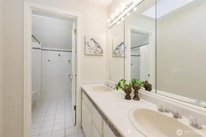 Double sinks adorn the second full bath on the upper level.    Though the doorway, you will find a tub, shower and stool.