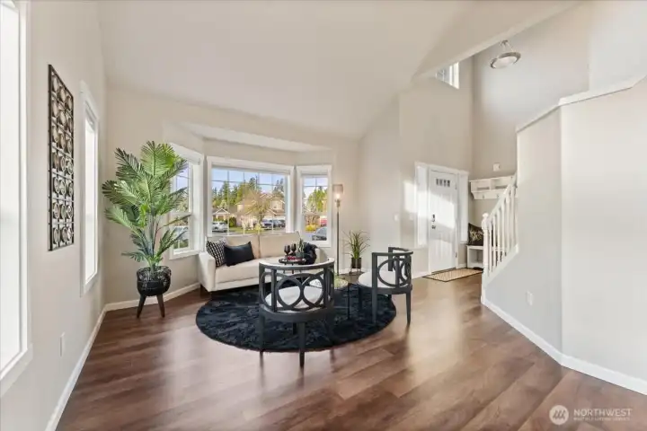 The living room is light and bright, filled with natural light and enhanced by high ceilings that create an open, airy feel.