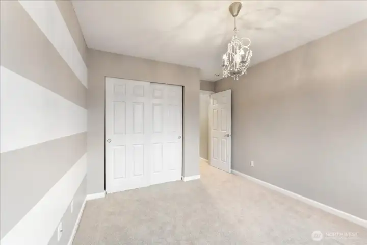 The white and gray striped bedroom adds a charming designer touch, creating a bright and cheerful space with personality.