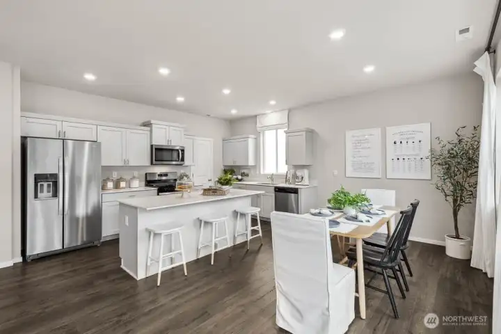 Open concept kitchen and dining area with big island and breakfast bar. Actual home is under construction. Colors, materials, and features may vary. See site agent for details.