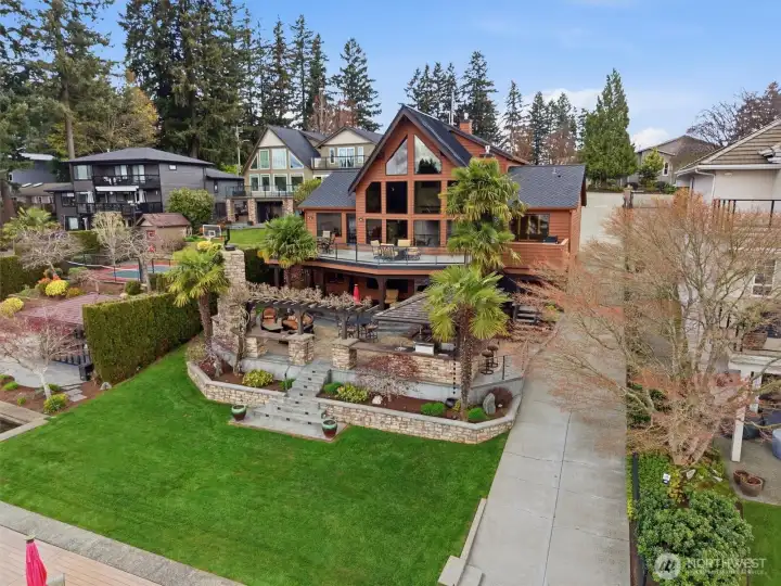 Expansive outdoor entertaining areas including deck, covered patio, firepit seating area, outdoor kitchen in cabana bar and flat lawn space off the lake.