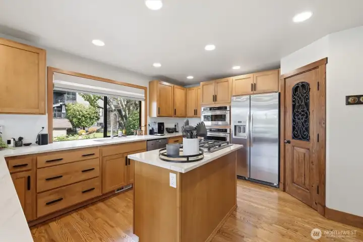 Center island with gas cooktop.  Pantry door is right of the fridge.