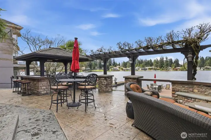 Spacious patio with steps in the middle leading to the grass and dock.