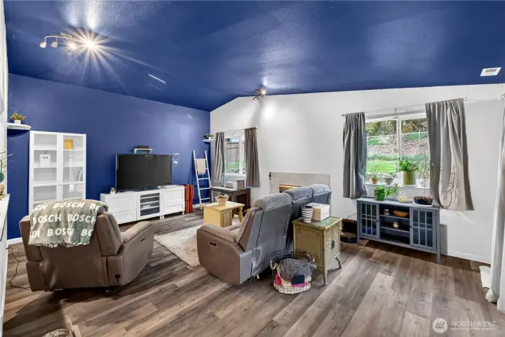 Striking vaulted living room with bold design, abundant natural light, and a cozy fireplace—an inviting space to relax or gather.