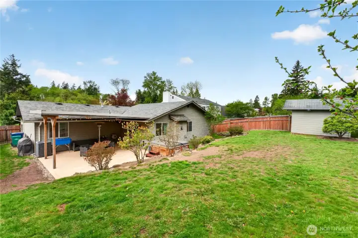 Spacious backyard with room to play, garden, or relax—complete with a storage shed and natural backdrop.