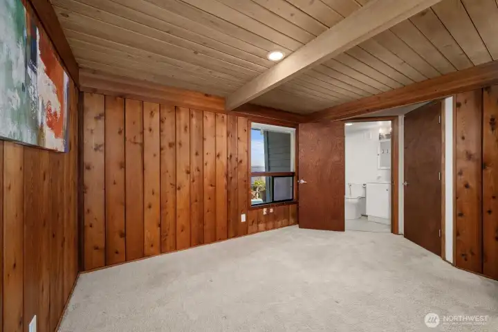 View of Primary Bedroom with large window of backyard and bay. Easy access to bathroom and walkin closet.