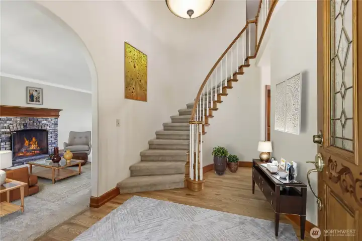 Main Entry offers archetectial style with curved wall, grand staircase, wood floors and arch to living room.