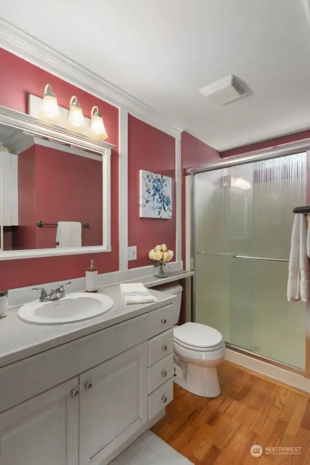 Main level 2nd bathroom.  Cute bathroom that would be perfect with some personalized touches but also wonderful as-is. Large walk in shower and longer vanity for storage plu storage behind the door.  All topped off with gleaming hardwood floors.