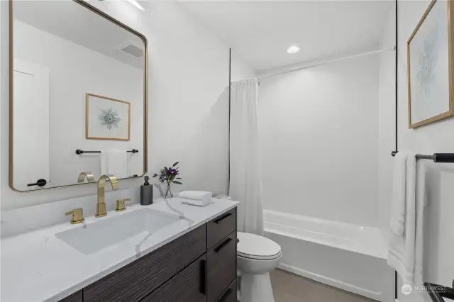 Elegant bathroom featuring gold fixtures and a full-size tub for a relaxing retreat.