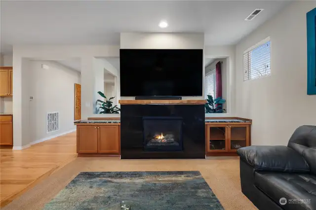 Living Room features gas fireplace, natural light, and a window that looks out to the covered patio with outdoor fireplace.