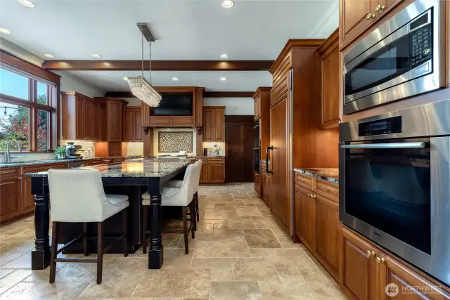 A grand kitchen with space for all and an impressive appliance package, featuring Sub Zero fridge with cabinet face, Wolf - 4 burner gas range with griddle, Meile - convection ovens (2), warming drawer, & steam oven. Kitchen Aid - beverage fridge & ice maker and new Bosch dishwasher.