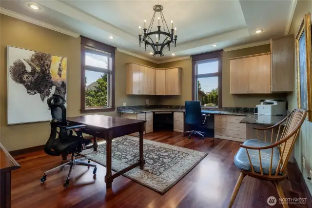 Large office space with built-in work stations, windows looking out to the rear yard and patio.