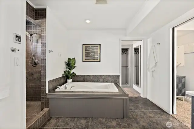 Primary bedroom en-suite with tile shower and soaking tub - access to the large custom walk-in closet.