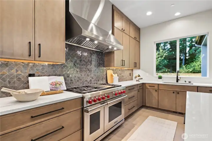 Impressive focal point with the 48” Wolf gas range with double-ovens, six-burners, and a griddle. Cabinets provide loads of storage extending all the way to the ceiling.