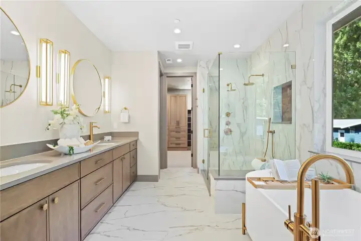 Divine shower wrapped in large-format floor-to-ceiling porcelain tile which lines one side of the bathroom, two shower heads, recessed shampoo niche. Enjoy a bubble bath escape in the modern, oval freestanding soaking tub elevated on sleek gold pedestal legs. Statement tub-filler with shower wand and cozy heated floors.