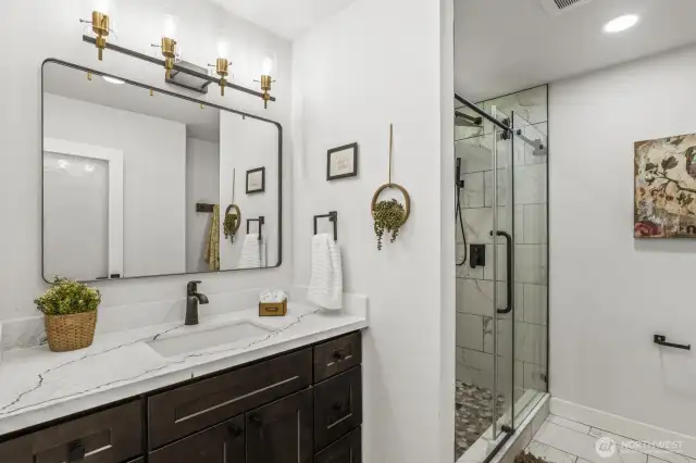 Gorgeous, fully remodeled primary bathroom featuring quartz countertops, designer tile, and a stunning walk-in shower with full tile surround.