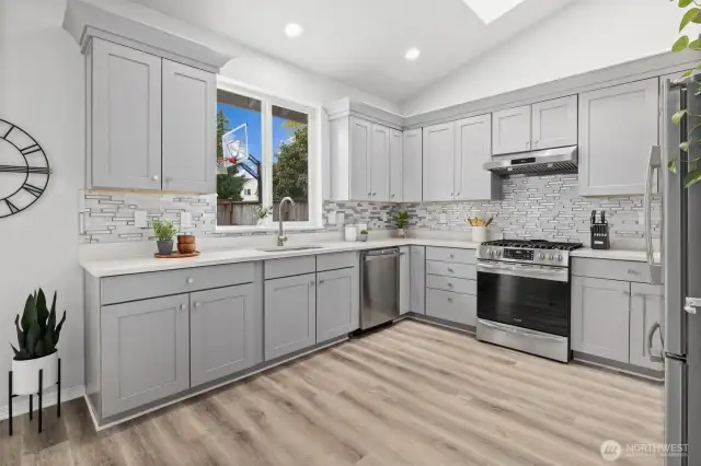 Bright and cheery kitchen with ample quartz countertops space with high ceilings, skylights and overlooking private backyard. All appliances stay.