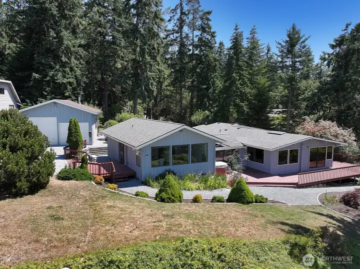 West side of your home. Shop with wood stove is on the far left. Three windowed part of the home (center) is the Primary Suite that can live as a separate guest suite/living area. Far right is the main house.