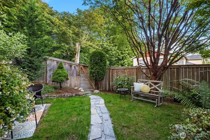 Flagstone steps lead to a back yard gate. The back yard is fully fenced.
