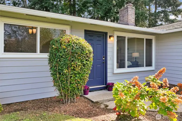 A closer look at the entry reveals a bold front door framed by landscaped beds. The covered approach creates a warm first impression and highlights the home’s inviting style.