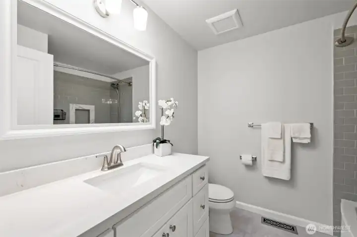 The full bathroom on the main level is finished with a wide vanity, framed mirror, and updated fixtures. Clean design and ample counter space add to its appeal.