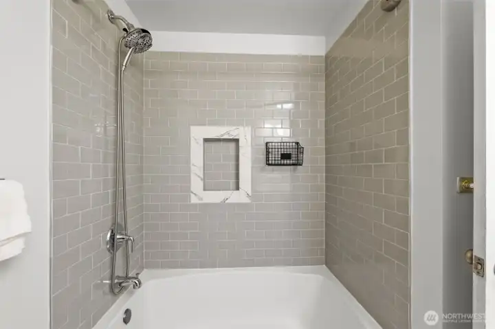 A closer look at the full bath reveals the tiled tub and shower combination, complete with a recessed niche for convenience.
