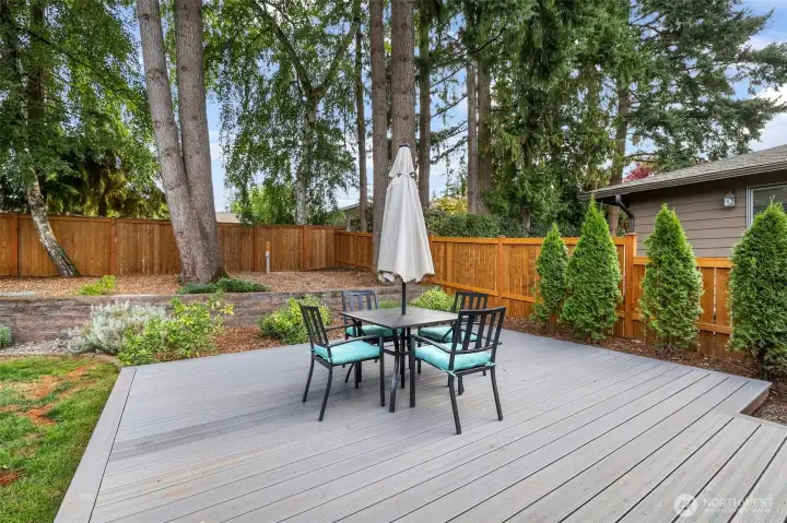 The deck extends the home’s living space into the outdoors, bordered by mature trees for a private and serene setting.