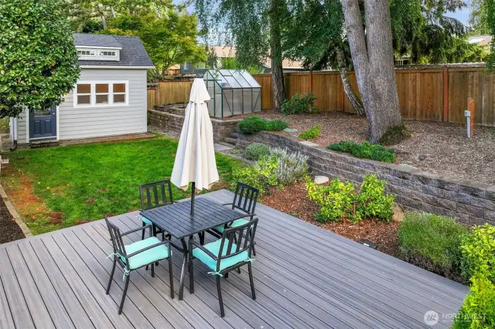 Another view of the yard and deck highlights the thoughtful landscaping, tiered beds, and extra space for gatherings.