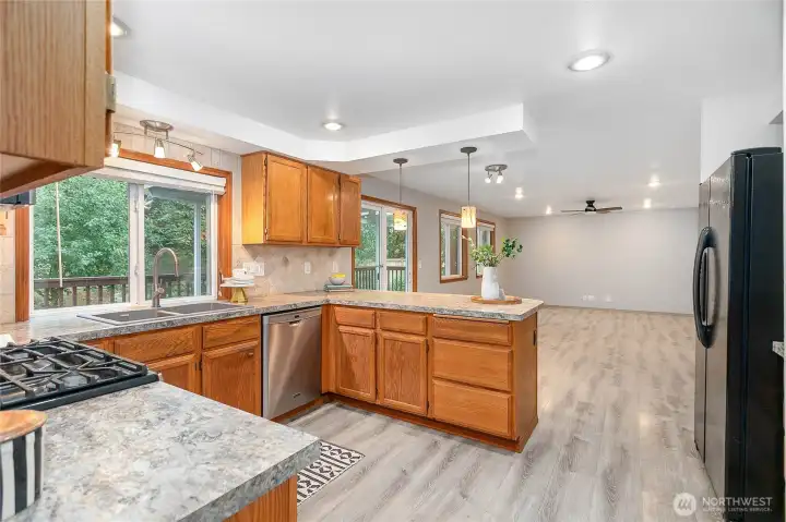 Spacious remodeled kitchen with upgraded appliances, tile backsplash, new sink, faucet, garbage disposal, and lighting elements.