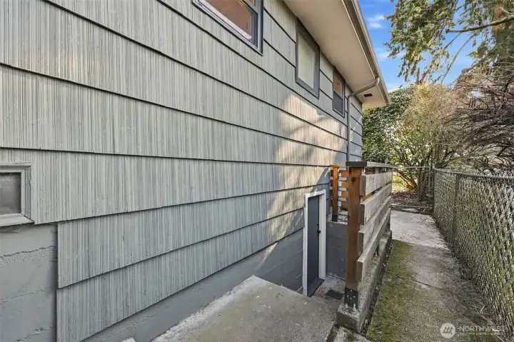 Entrance to the basement is on the west side of the house.  The wooden fence was added during ownership.