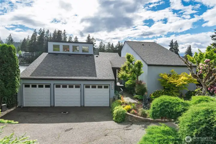 Driveway shows private mature landscape.