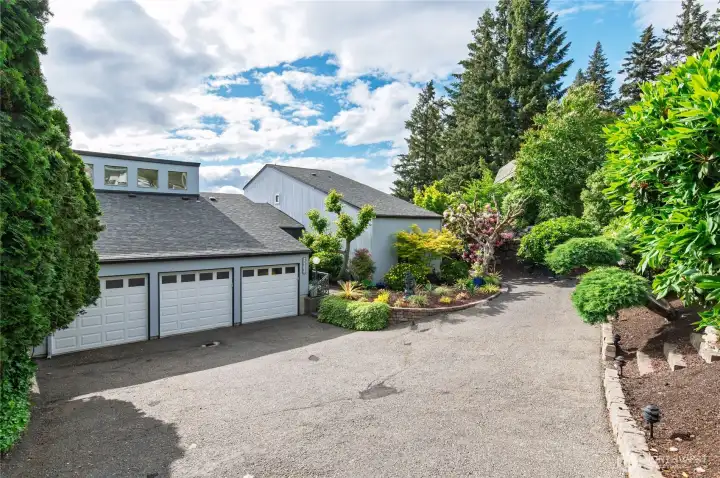 Driveway shows private mature landscape.