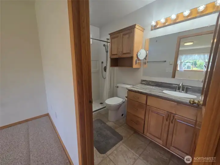 Primary bath features a zero-entry shower with attached shower chair, generous vanity storage, and convenient accessibility-focused design.