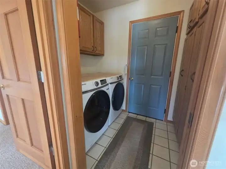 Dedicated utility room with washer and dryer, abundant storage, built-in cabinetry, and direct access to the attached two-car garage.