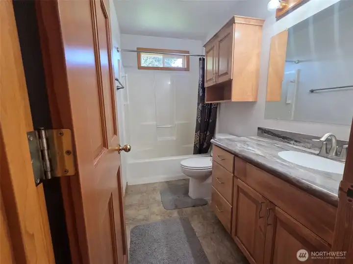 Bright guest bath features a full tub/shower combination (with grab bars), updated vanity, abundant storage, and natural light from a privacy window.