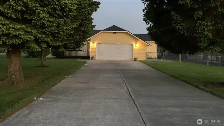 Warm exterior lighting, mature landscaping, and a spacious driveway create a welcoming first impression and beautiful evening curb appeal.