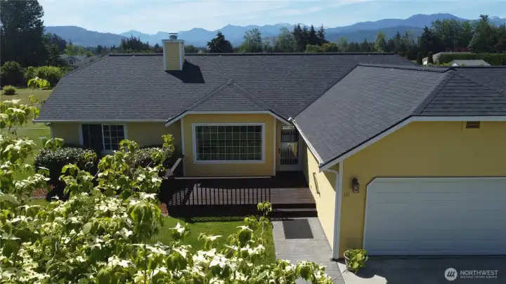 Drone shot of the front of the house through the blooming dogwood tree with the mountains standing tall in the distance.