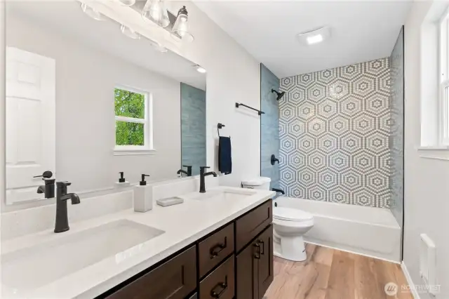 Primary En Suite Bath w/Luxurious Dual Sink Vanity, Laminate Floors and Custom Tile Shower Surround.
