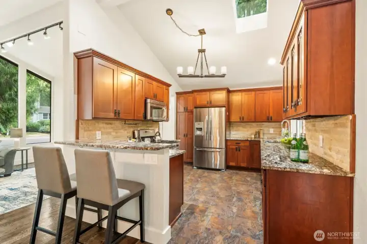 Custom cabinets highlight this remodeled chef's kitchen. Don't miss the vaulted ceilings, skylight, and chandelier lighting.